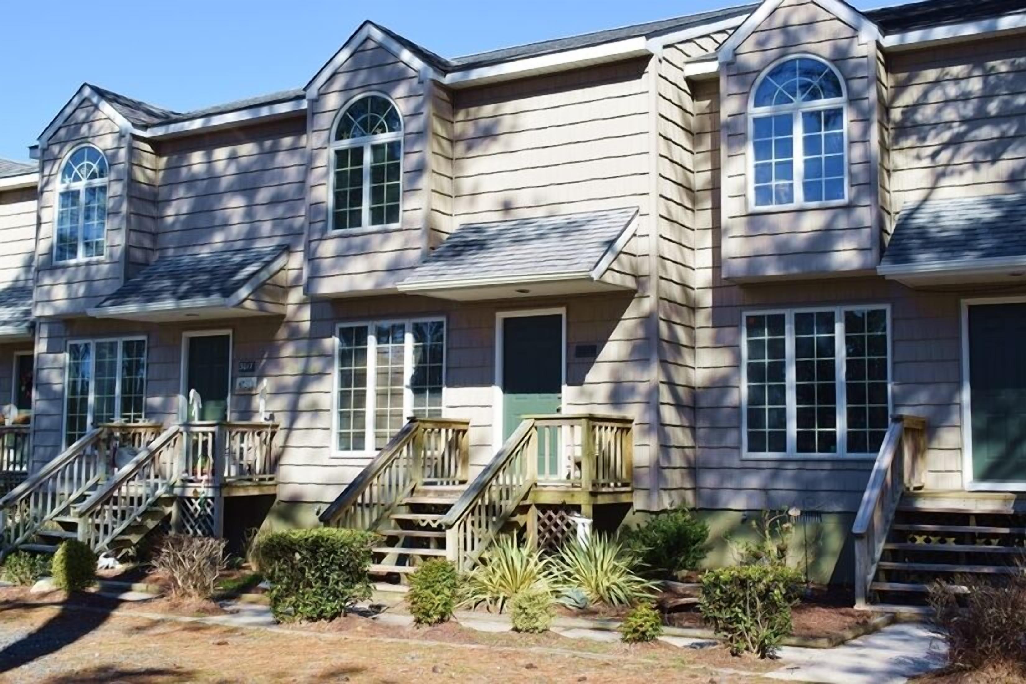 Una hilera de casas adosadas con porches individuales, una escalera central y un pequeño jardín.