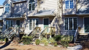 A row of townhouses with individual front porches, a central staircase, and a small garden area.