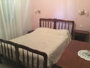 Ein Schlafzimmer mit einem hölzernen Bett, einem kleinen Nachttisch und einem Beistelltisch.