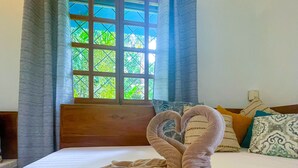 A hotel room with a bed, a window with curtains, and a view of greenery outside. - Latitude Adjustment, Heart of Manuel Antonio, 1BD (Quepos)
