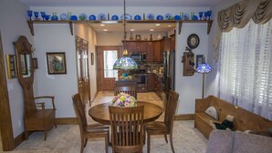 A dining area with a round table, wooden chairs, and a floral centerpiece. - 2 BR | Screened Porch | Walk to Town (Chincoteague)