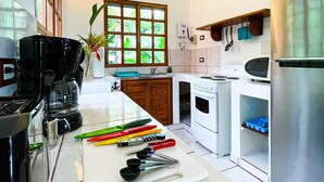 A modern kitchen with a large island, stainless steel appliances, and a window with a view of greenery.