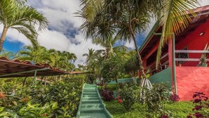 A garden with a green pathway, palm trees, and a red building.