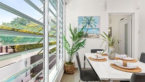 Zona pranzo con una grande finestra, un dipinto di una spiaggia e piante in vaso.