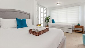 Una moderna camera d'albergo con un letto grande, un comodino, un piccolo tavolo da notte, una finestra con tende e una pianta in vaso.