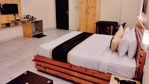 Una habitación de hotel con cama, escritorio, televisor y armario.