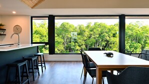 Et moderne køkken med et stort vindue, træloft og et spiseområde med et bord og stole.