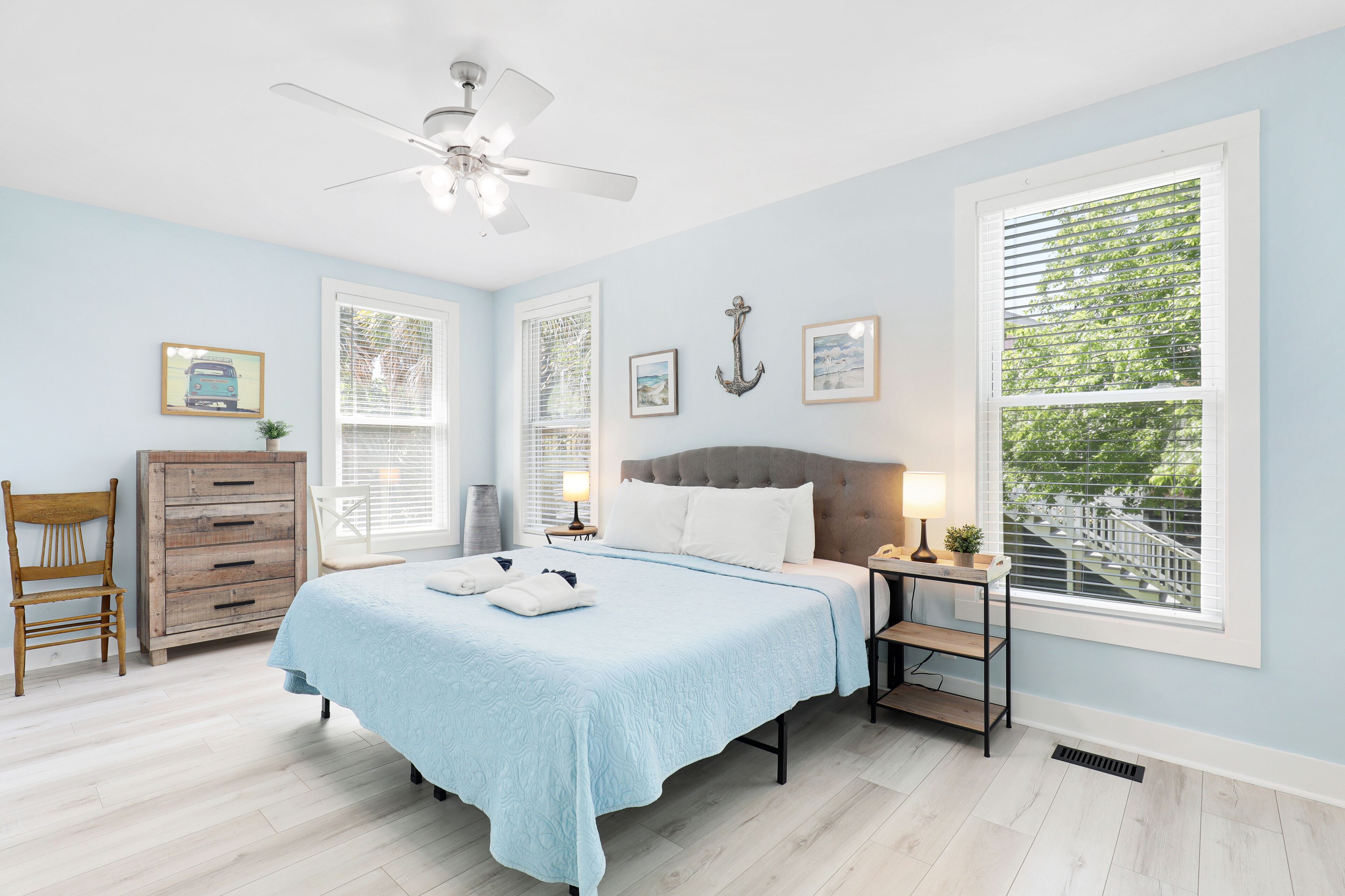 A bedroom with a bed, a dresser, a chair, a nightstand, and a window with blinds.