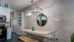 Een moderne keuken met witte kastjes, een houten aanrecht, een ronde spiegel en een hanglamp.