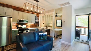 A modern kitchen with stainless steel appliances, a built-in oven, and a hanging light fixture. - In-town Couples Getaway with Dockslipl (Holderness)