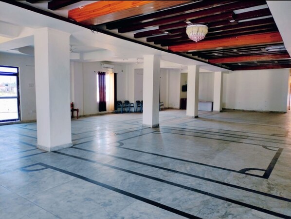A spacious indoor area with a high ceiling, exposed wooden beams, and a chandelier.