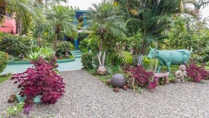 Un jardin où l’on trouve une variété de plantes, une statue de vache décorative et une petite figurine humaine.