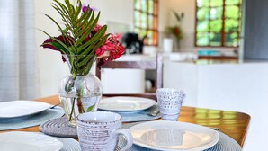 Une table à manger dressée avec des assiettes, des bols et un vase rempli de fleurs.