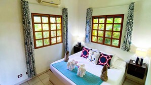 Une chambre d’hôtel comprenant un lit, deux tables de chevet, une fenêtre avec des rideaux et un appareil de climatisation.