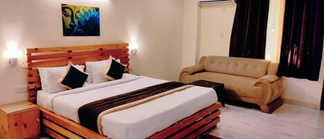 A bedroom with a wooden bed, a sofa, a red rug, and an air conditioning unit.