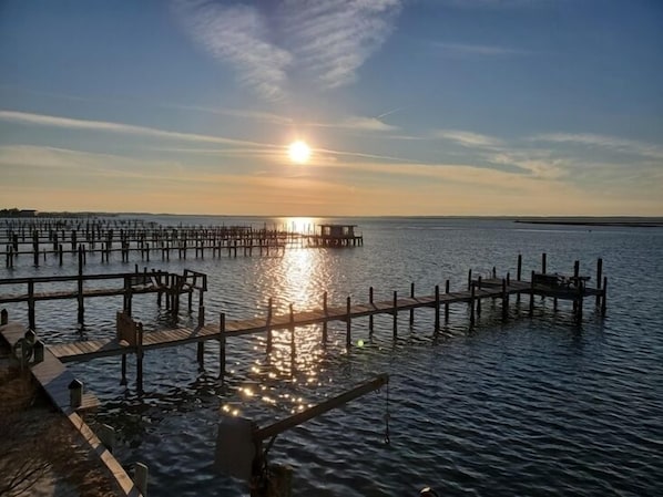A pier extending into calm water with a sunset in the background.