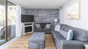 Una sala de estar moderna con un sofá gris, un televisor de pantalla plana y una chimenea.