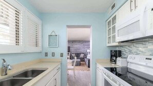 Una cocina con armarios blancos, un lavamanos doble y un microondas.