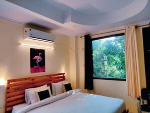Relax in a cozy retreat with a comfortable bed, air conditioning, and a serene view of the surrounding greenery.