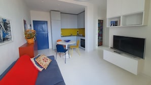 A modern living room with a sofa, a TV, and a dining area with chairs and a table. - Apartment with a/c far 50 m from the sea (Viareggio)