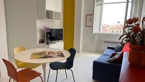 A modern living room with a round table, two chairs, a sofa, and a TV. - Apartment with a/c far 50 m from the sea (Viareggio)