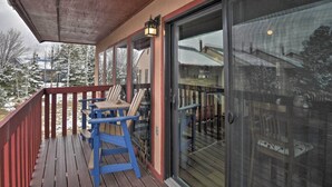A covered outdoor area with a wooden deck, blue chairs, and a glass door leading to an interior space. - Nicely renovated two bedroom two bath Condo with Lake and Mountain Views! (Pagosa Springs)