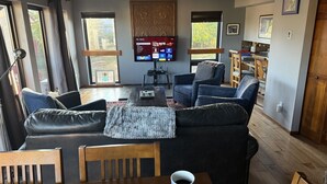 A living room with a sofa, chairs, a coffee table, and a TV mounted on the wall. - Nicely renovated two bedroom two bath Condo with Lake and Mountain Views! (Pagosa Springs)