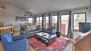 A spacious living room with a sofa, armchairs, a coffee table, and large windows with curtains. - Nicely renovated two bedroom two bath Condo with Lake and Mountain Views! (Pagosa Springs)