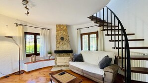Una sala de estar con chimenea de piedra, una escalera curva, un sofá y una mesa de centro.