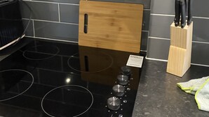 A kitchen with a black induction cooktop, a wooden cutting board, and a knife block. - Large 3 bed House Sleep 10 Anfield Liverpool (Liverpool)
