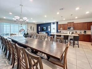 A spacious kitchen with a large island, wooden chairs, and a dining table.