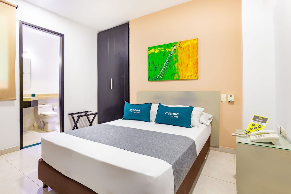 Een hotelkamer met een bed, een bureau met een telefoon en een schilderij aan de muur.