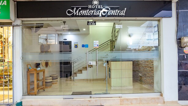 The exterior of Hotel Monteria Central with a clear glass entrance, a staircase leading inside, and a visible reception area.