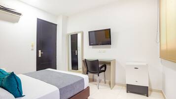 A hotel room with a bed, a desk, a chair, a TV, and a small cabinet.