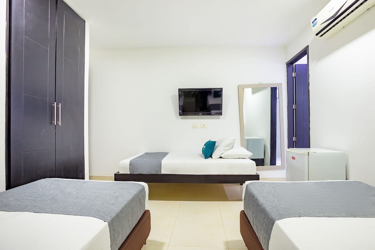 Een hotelkamer met twee bedden, een televisie, een spiegel, een kledingkast en een kleine koelkast.