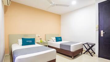 A hotel room with two beds, a ceiling fan, a small table with a phone, and a dark door.