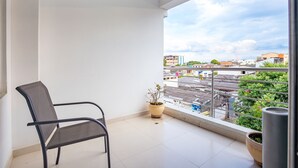 A balcony with a chair, a potted plant, and a view of the cityscape.