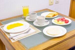 Una mesa de desayuno con tostadas, fruta y una taza de café.