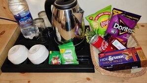 A tray with a bottle of Aquafina water, a kettle, two glasses, and various snacks including Lay's chips, Doritos, Amulya, and chocolate rolls. - Suite with Balcony 2 (Ramnagar)