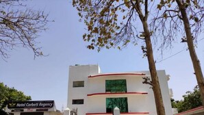The exterior of Hotel Corbett Regency with a clear entrance, a gated driveway, and a parking area. - Suite with Balcony 2 (Ramnagar)