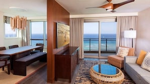 Uma sala de estar ampla, com uma grande mesa de jantar, assentos confortáveis, televisão e vista para o oceano.