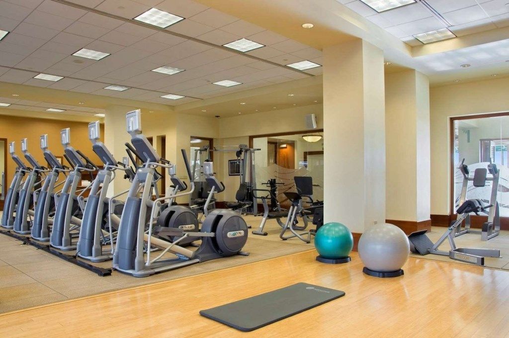 A gym with multiple treadmills, exercise balls, and a mirror wall.
