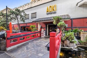 A restaurant with a red and white facade, a stone pathway, and a small pond with fish. - Waikiki | Oceanview Luxe Stay | Resort Pool & Beach (Honolulu Oahu)