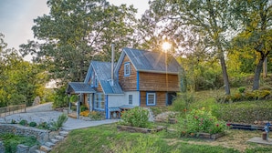Una casa a due piani in legno con tetto blu e un vialetto in pietra che conduce all'ingresso.