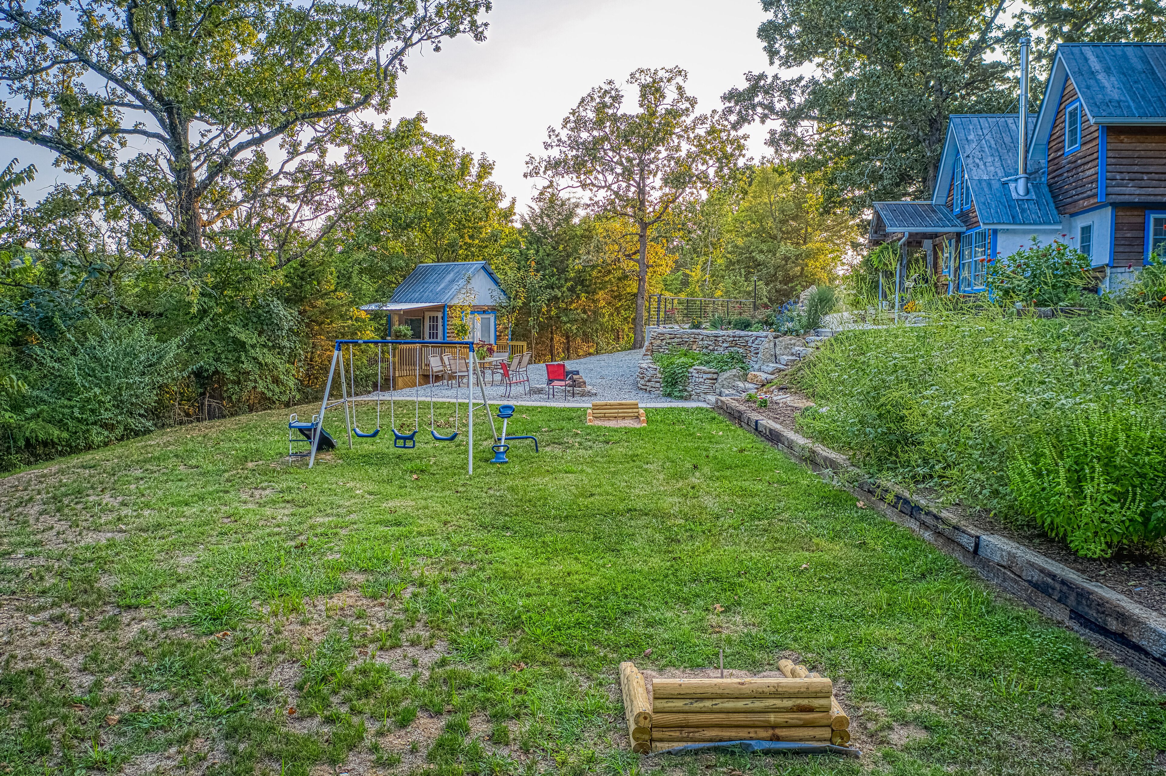 Un jardin avec une balançoire, un petit abri de jardin et un banc en bois.