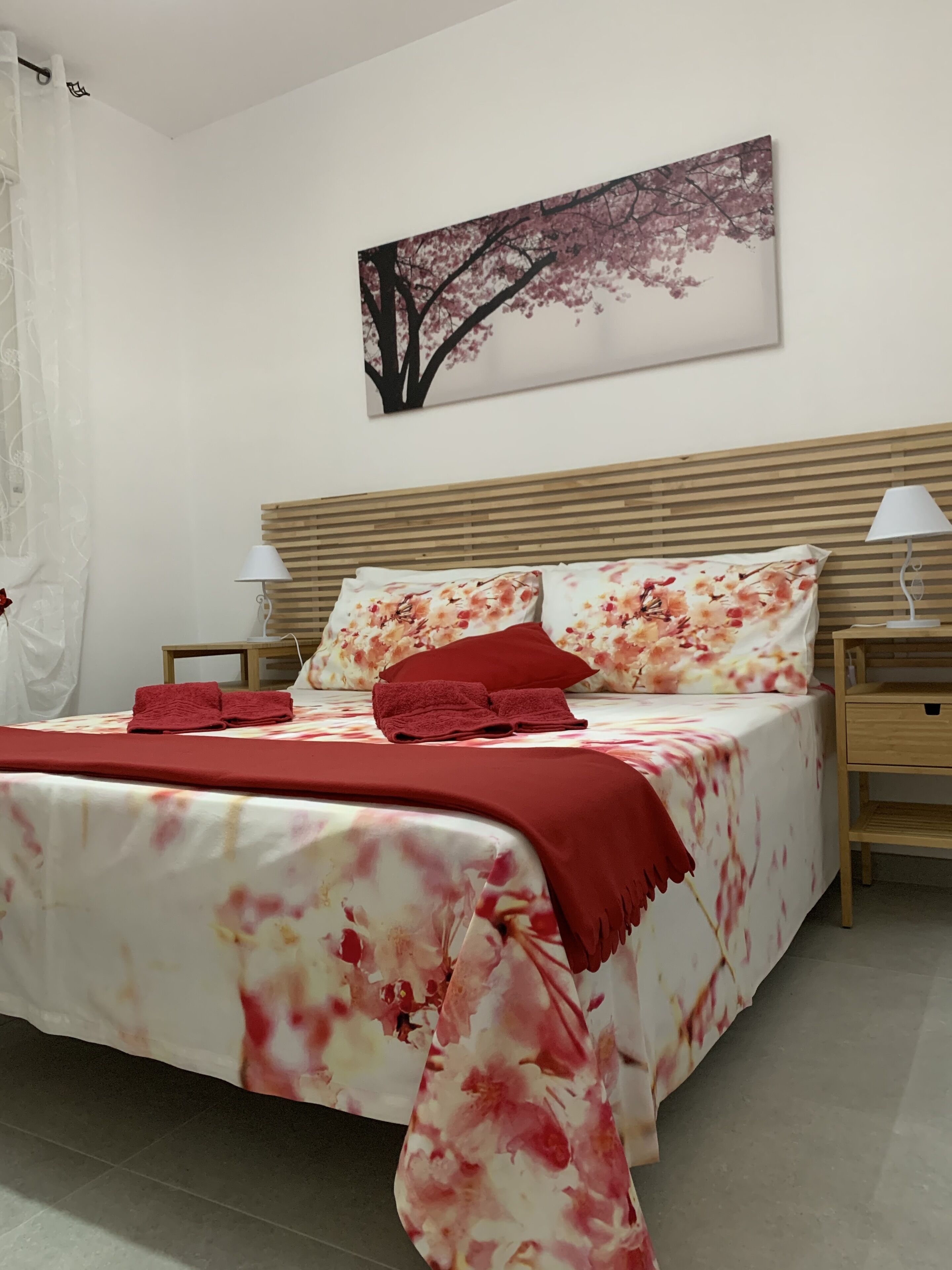 A neatly made bed with floral bedding, a wooden headboard, and two bedside tables with lamps.