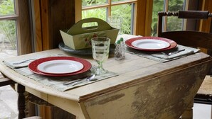 Ein Tisch ist gedeckt mit Tellern, einem Glas und Besteck, im Hintergrund ist ein Fenster zu sehen.