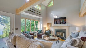 A spacious living room with a fireplace, large windows, and a cozy seating area.