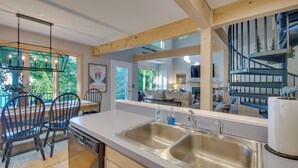A modern kitchen with a large island, stainless steel sinks, and a dining area with chairs.