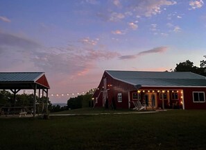 A red barn with a metal roof and a covered area with a red roof.